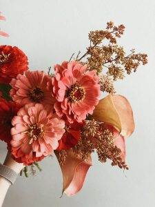 A delicate bouquet featuring vibrant Zinnias and elegant Calla Lilies against a soft background.
